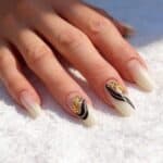 Manicure gel con nail art geometrica nera e oro su unghie a mandorla