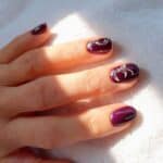 Manicure gel viola lucido con nail art astratta su unghie naturali